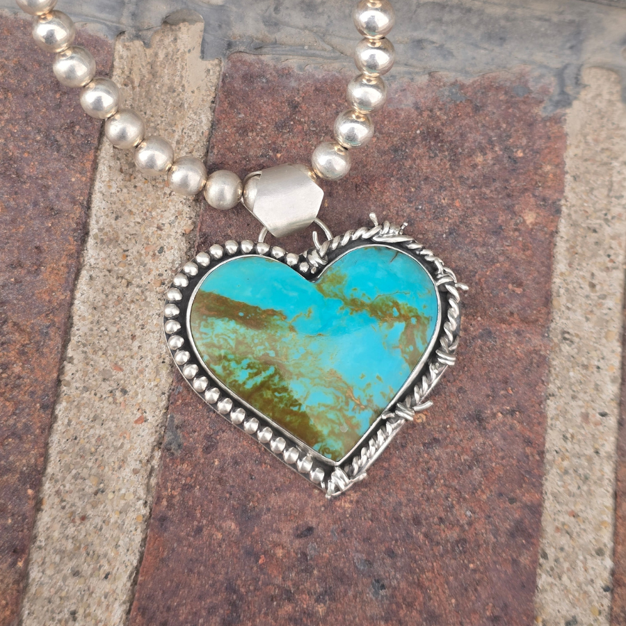 Necklace with a heart-shaped turquoise pendant on a textured surface