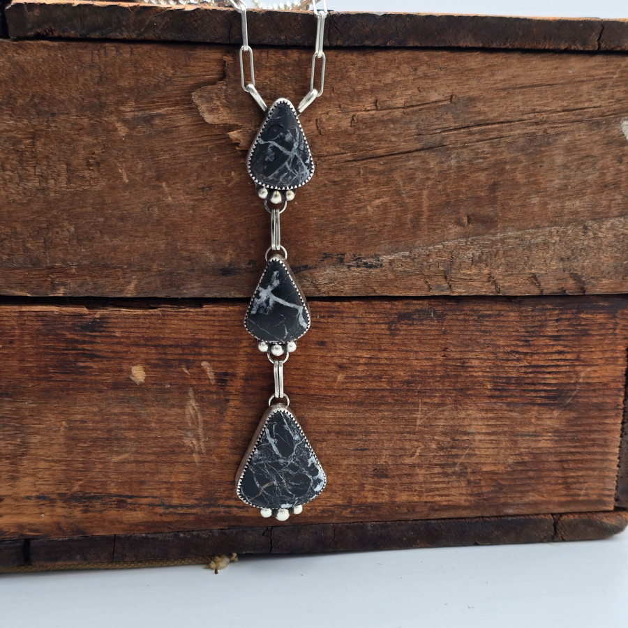 Necklace with black teardrop-shaped pendants on a wooden surface