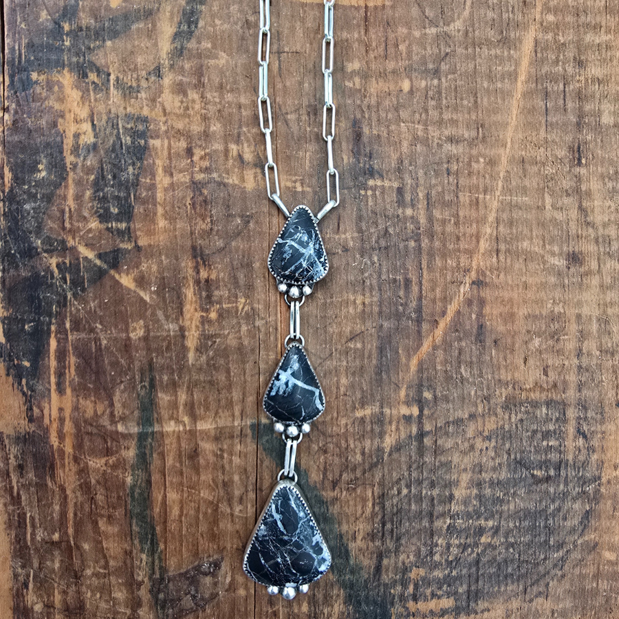Necklace with three dark stone pendants on a wooden surface